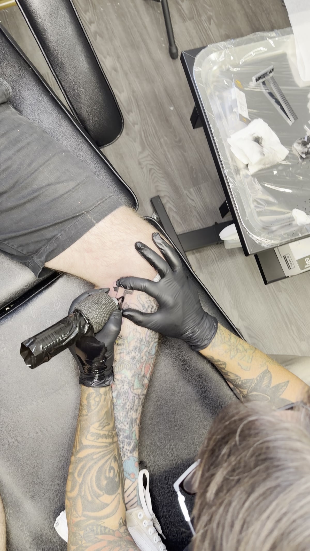 Tattoo artist working during an authentic client session inside Barber Skate Shop